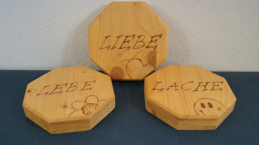 LEÑA Kunsthandwerk: Drei achteckige Holzschilder mit Brandmalerei, Made in Austria. Beschriftet mit LEBE, LIEBE, LACHE