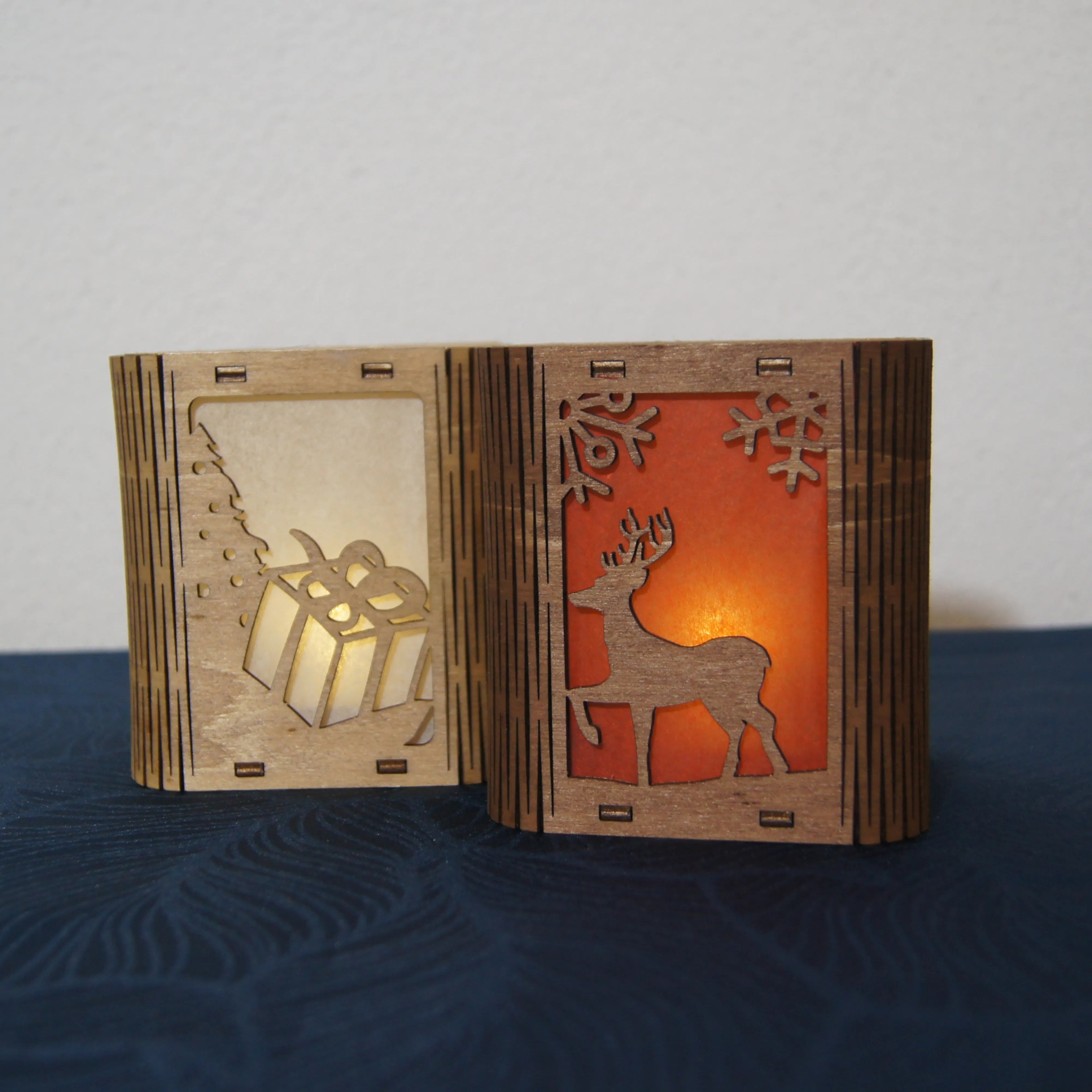 Zwei LEÑA Kunsthandwerk Holz-Laternen mit LED-Licht, eine mit Geschenk und Baum, die andere mit Hirsch und Schneeflocken